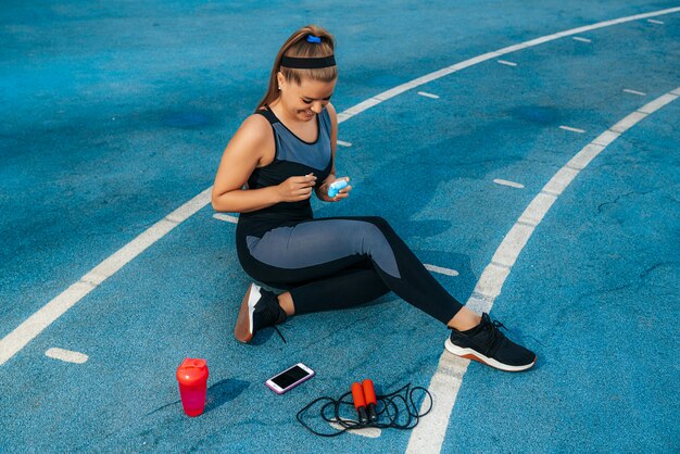 Woman sits on the playground and puts on earphones