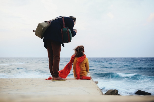 Woman sits on the quay and the man is taking photo of her