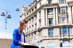 Free photo woman sits on the street and works with a laptop