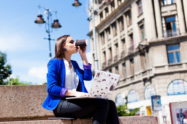 Woman sits on the street and works with a laptop