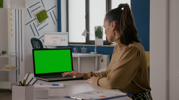 ノート​パソコン​の​緑色​の​画面​で​机​に​座って​、​クロマキーテンプレート​と​孤立した​モックアップ​の​背景​で​作業している​女性​。​クロマキーモックアップコピースペース​が​展示されている​コンピューター​を​使用している​人​。