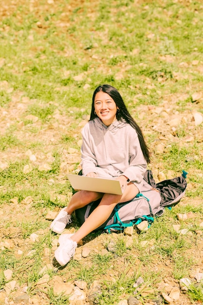 Free photo woman sitting on backpack with notebook and looking at camera