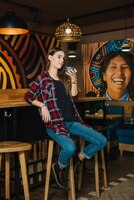Woman sitting on bar chair with coffee in cafe