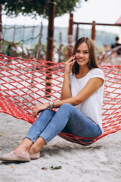 Woman sitting at the beach and talking on the phone