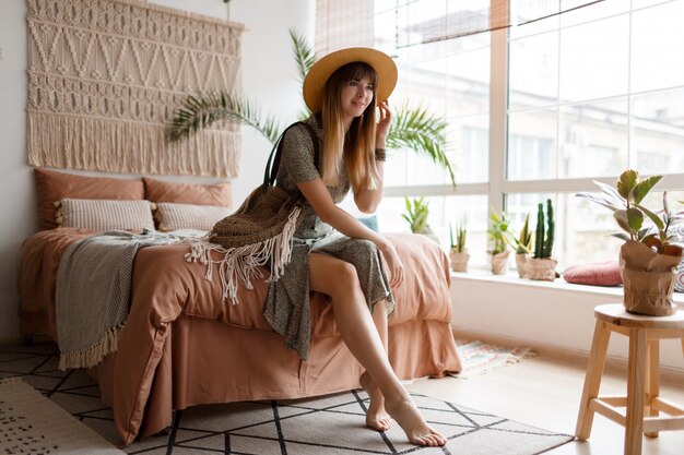 Woman sitting on bed in her boho apartment