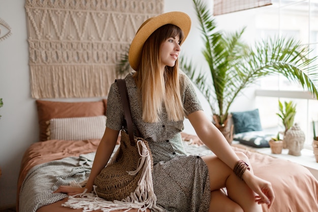 Woman sitting on bed in her boho apartment