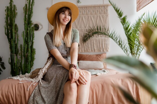 Woman sitting on bed in her boho apartment