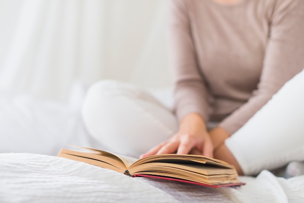 Foto gratuita donna che si siede sul letto a leggere il libro