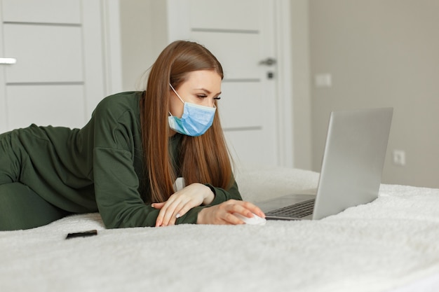 Free photo woman sitting on a bed and uses a laptop