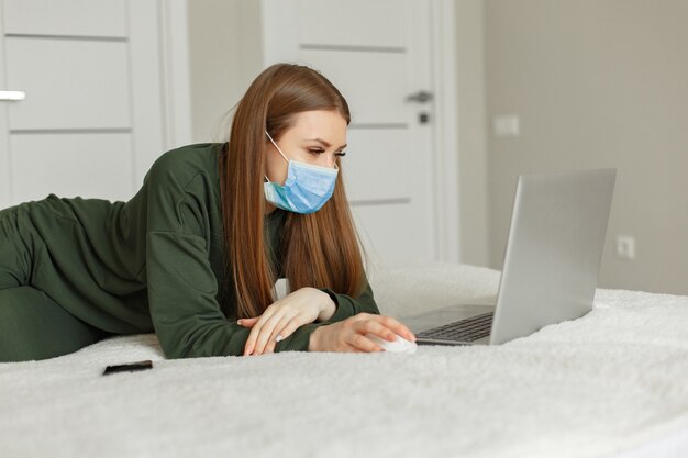 Woman sitting on a bed and uses a laptop