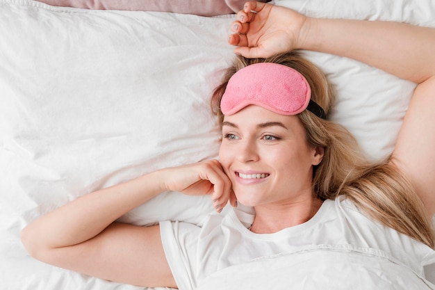 Woman sitting in bed with sleep mask