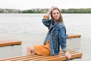 Free photo woman sitting on bench at seaside