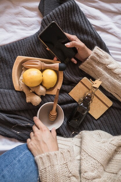 携帯電話で毛布に座ってジュースを作る女性