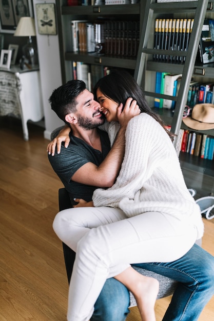 Free photo woman sitting on boyfriend's lap sitting on chair at home