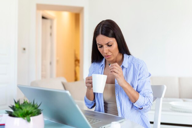 オフィスの机のそばに座って薬を飲んでいる女性このインフルエンザがすぐに消えることを願っていますインフルエンザにかかっている実業家私は病気で1日休むべきでした