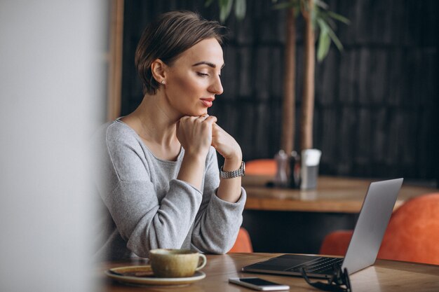 Woman sitting in a cafe drinking coffee and working on a computer