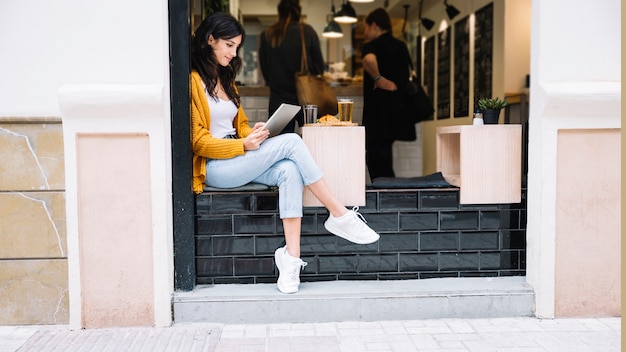 Woman sitting at cafe table with tablet