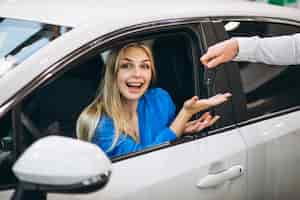 Free photo woman sitting in car and receiving keys in a car showroom