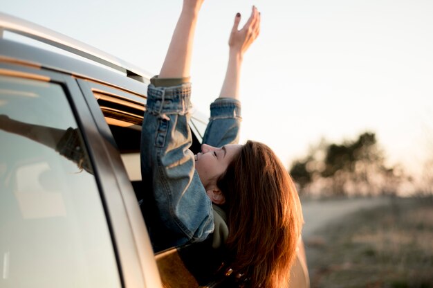 彼女の手と頭を屋外で車に座っている女性