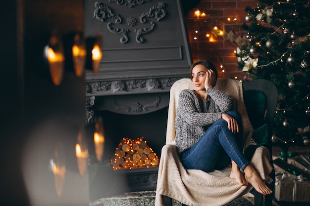 Woman sitting in chair by Christmas tree