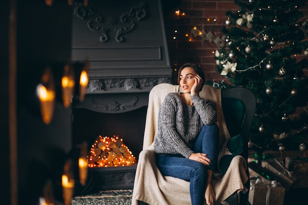 Woman sitting in chair by Christmas tree