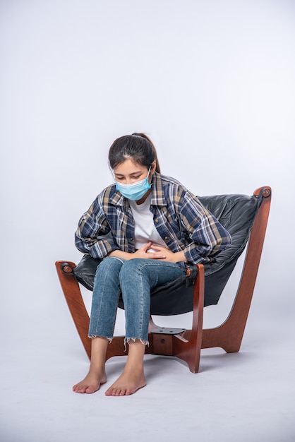 Free photo a woman sitting in a chair with abdominal pain and pressing her hand on her stomach