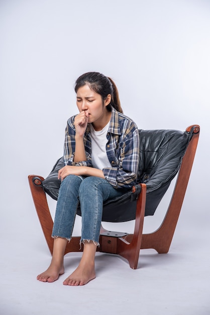 A woman sitting in a chair with abdominal pain and pressing her hand on her stomach