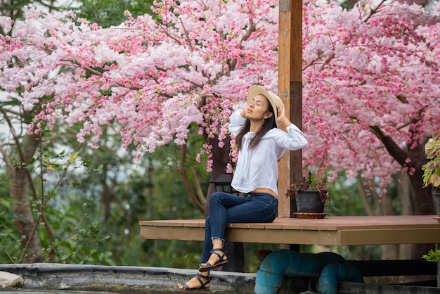 Foto gratuita la donna seduta sotto il ciliegio