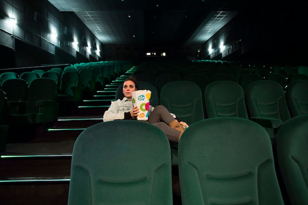 Woman sitting in cinema hall with popcorn