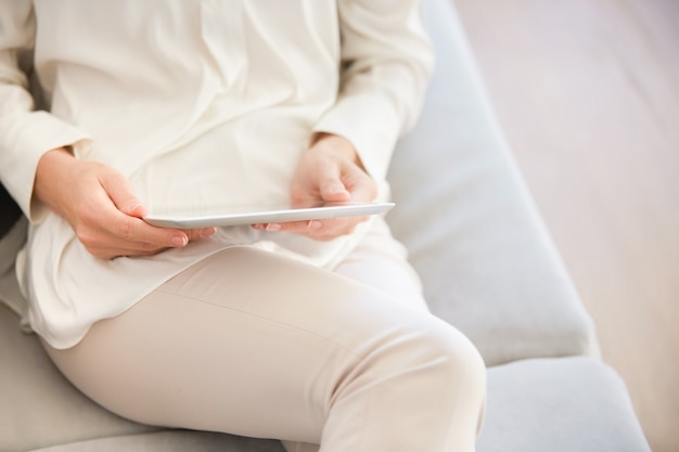 Woman sitting on couch and using tablet