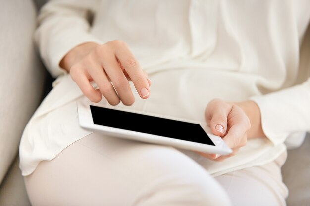 Woman sitting on couch and using tablet