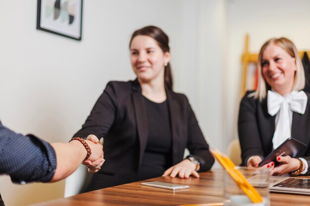 Woman sitting at desk shaking mans hand