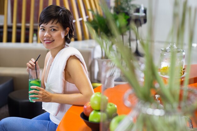 グリーンスムージーを飲んで座っている女性