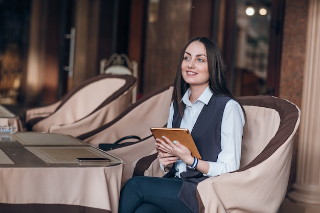 Foto gratuita donna che si siede in un elegante ristorante con una tavoletta