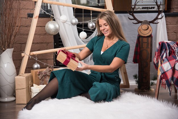 Woman sitting on the floor at home with Christmas presents