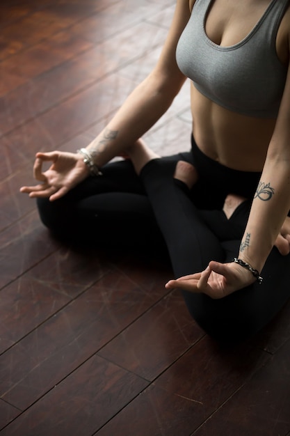 Woman sitting on floor in Padmasana pose, making mudra gesture