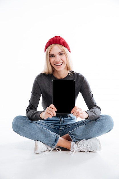 Woman sitting on the floor and showing blank screen tablet