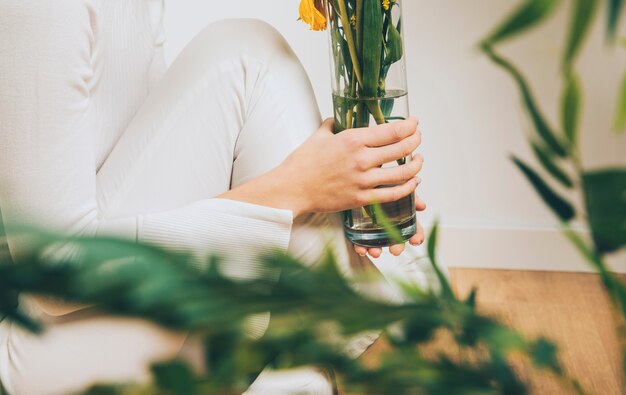 Woman sitting on floor with flowers in vase 