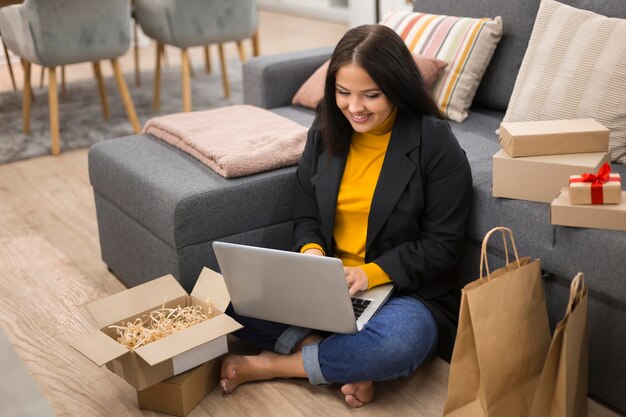 Foto gratuita donna seduta sul pavimento con il suo laptop in grembo