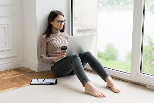 여자가 그녀의 노트북에서 일하는 바닥에 앉아
