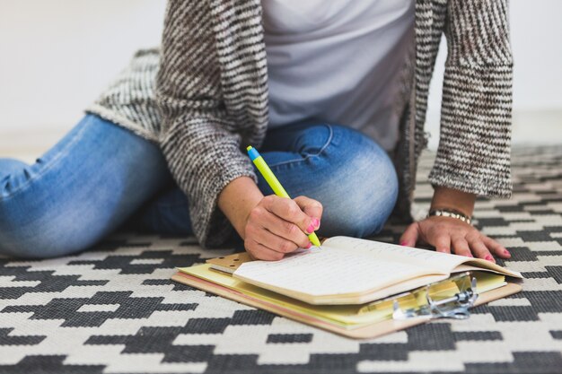 Woman sitting on the floor and writing in her notebook