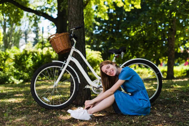 自転車の横にある森林の地面に座っている女性