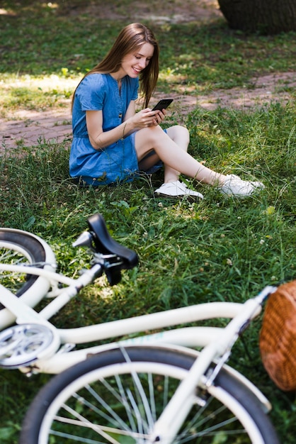 Free photo woman sitting on grass next to bike