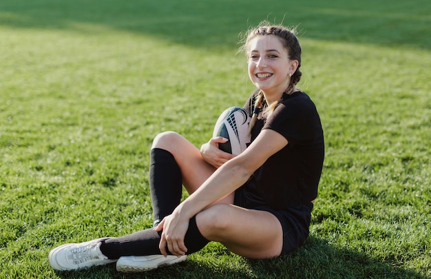 Free photo woman sitting on grass and holding a ball