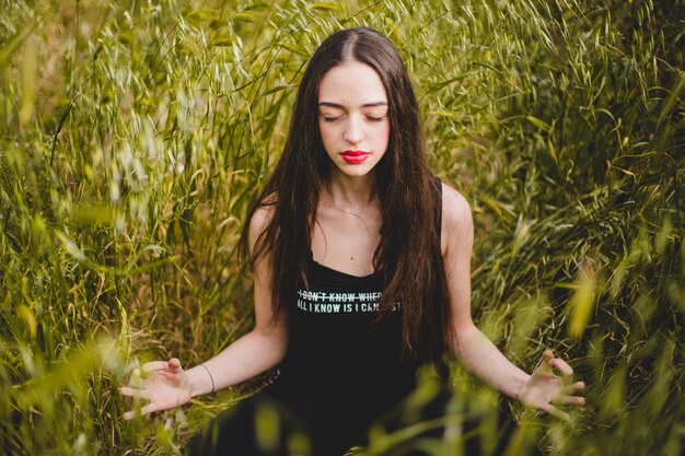 Woman sitting in grass and meditating