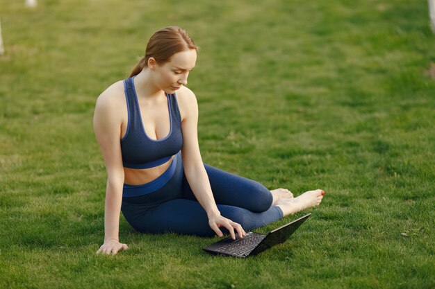 Woman sitting on a grass and uses a laptop