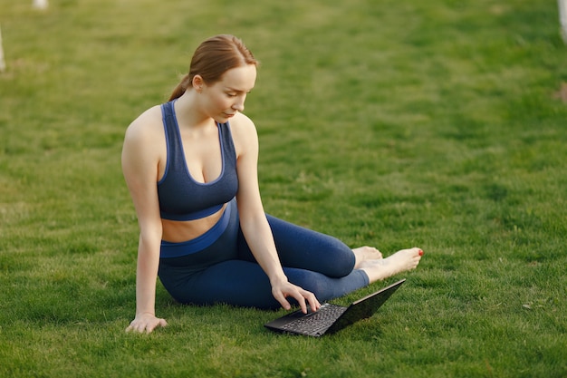 여자가 잔디에 앉아 노트북을 사용