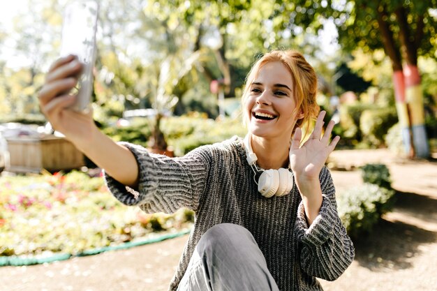 温室に座っている女性が自分の携帯電話で自分撮りをします