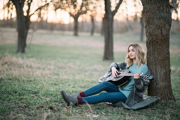 Woman sitting on ground with guitar