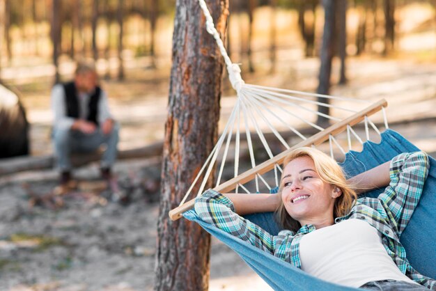 Woman sitting in hammock blurred man in background